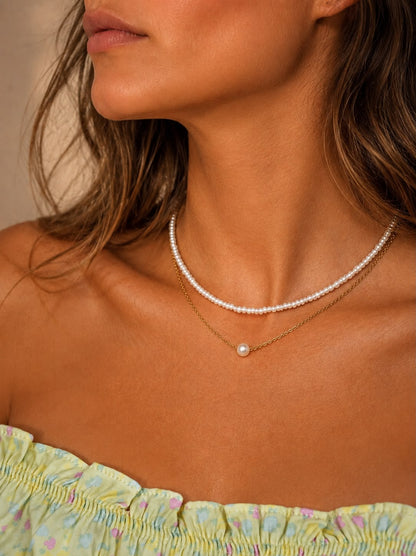Kvinna som bär Rizo pärlhalsband som choker mot huden