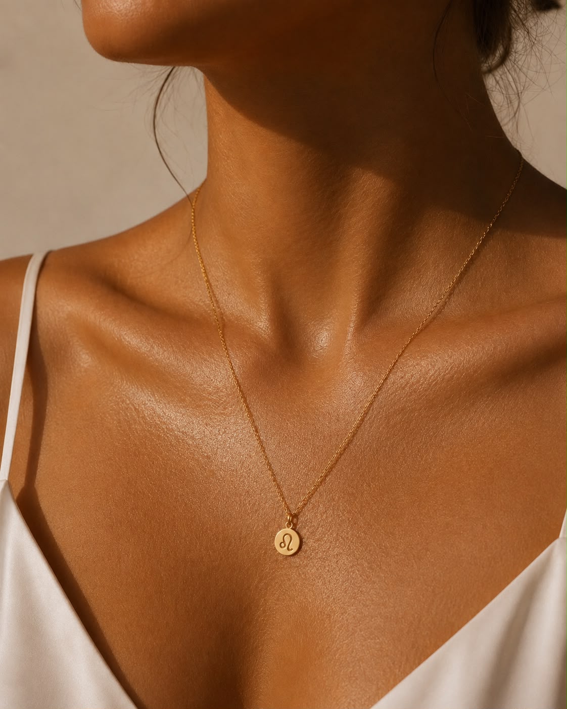 Kvinna som bär Rizo stjärntecken halsband med graverad berlock i guld