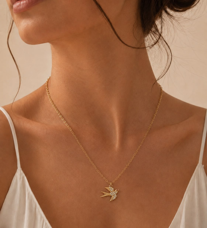 Kvinna som bär ett guldpläterat svalhalsband mot ljus topp i en avslappnad vardagslook.